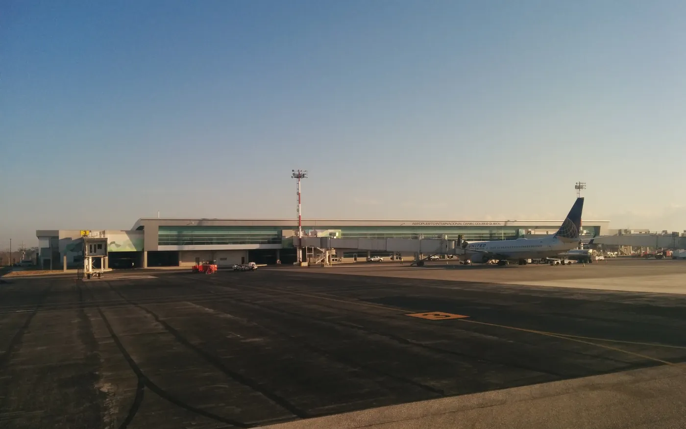 The terminal at Daniel Oduber Quirós International Airport in Liberia, Costa Rica, photographed from the apron at low sun, with an airliner parked at a gate