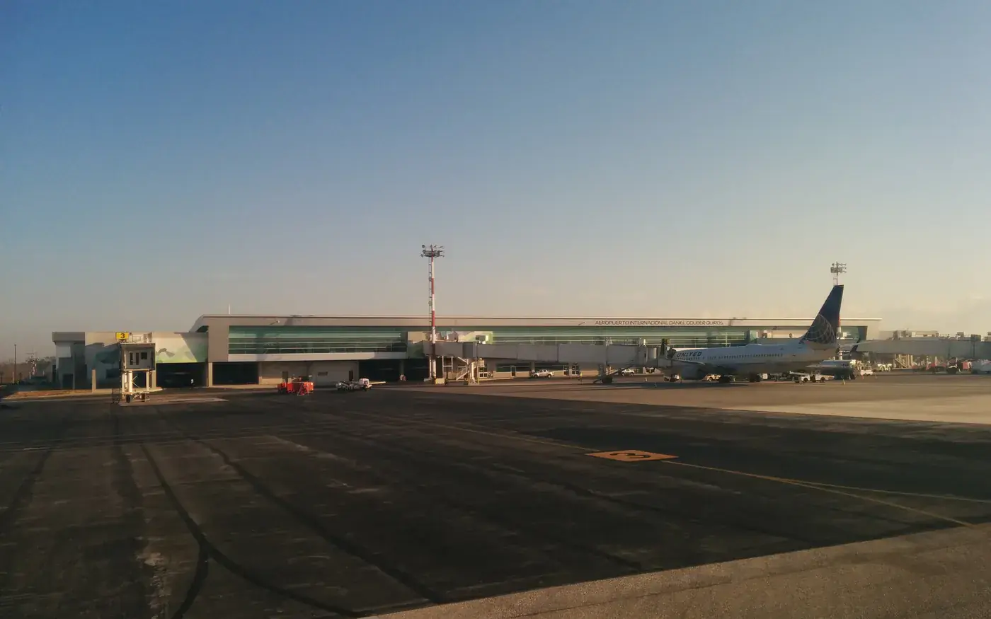 The terminal at Daniel Oduber Quirós International Airport in Liberia, Costa Rica, photographed from the apron at low sun, with an airliner parked at a gate