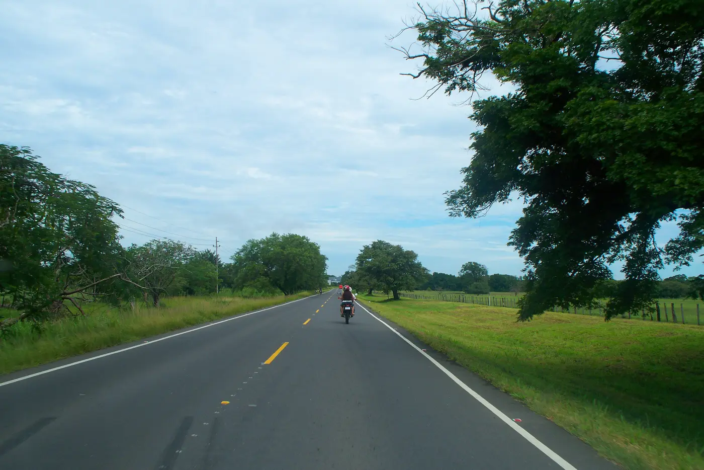 A two-lane stretch of the Pan-American Highway through green pastureland in Guanacaste, Costa Rica