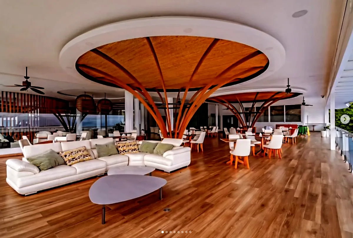 Interior of Cana Tico by day, white sofas and dining tables beneath fanned timber columns that open like palms into the ceiling